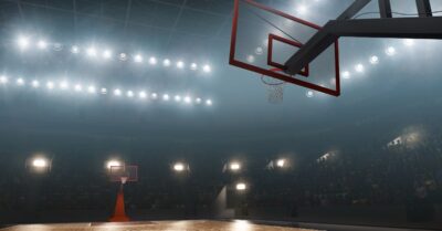 Photo of a dark basketball court with floodlights surrounding.