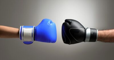 Image of two arms with boxing gloves on the end pointing at each other